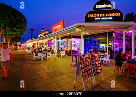 Lanzarote Canary Islands Bars, Geschäfte und Restaurants an der Ave Las Playas mit klarem dunkelblauem Abendhimmel Stockfoto