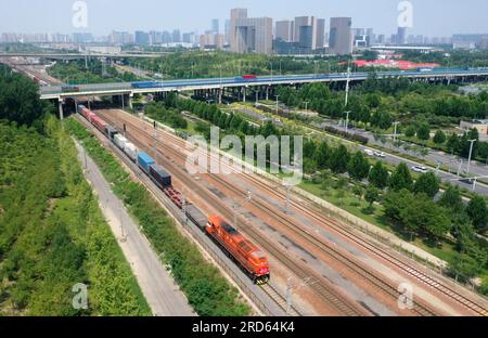 Zhengzhou, Deutschland verlässt den Bahnhof Putian in Zhengzhou. 18. Juli 2013. Dieses Luftfoto wurde am 18. Juli 2023 aufgenommen und zeigt einen Güterzug zwischen China und Europa nach Hamburg, der den Bahnhof Putian in Zhengzhou, der Hauptstadt der zentralchinesischen Provinz Henan, verlässt. Zhengzhou hat seit dem 18. Juli 2013 7.572 Güterzüge zwischen China und Europa abgefertigt, die 670.000 TEU (20 Fuß äquivalente Einheiten) beförderten. Kredit: Li Jianan/Xinhua/Alamy Live News Stockfoto
