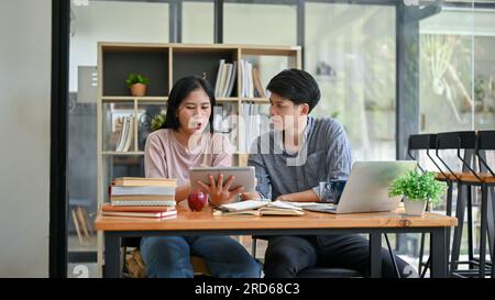 Zwei asiatische Freunde diskutieren über ihre Arbeit und arbeiten an ihrem gemeinsamen Projekt in einem Café, wo sie am Wochenende zusammenarbeiten. Kollege, Kollege, Freunde Stockfoto