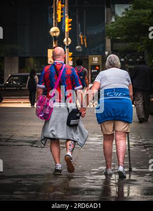 Foto von Senioren, die Händchen halten und draußen gehen. Rückansicht eines alten Paares, das Hand in Hand nach draußen geht. Straßenfoto, Reisefoto Stockfoto