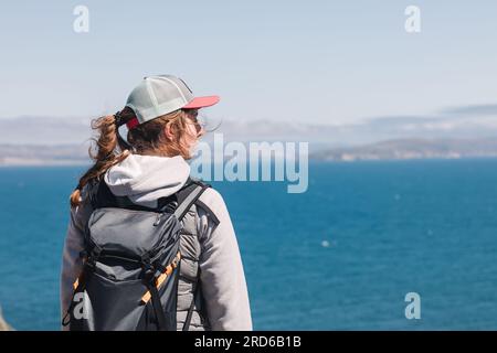 Eine Frau, die an einem windigen Tag auf den blauen Ozean schaut Stockfoto