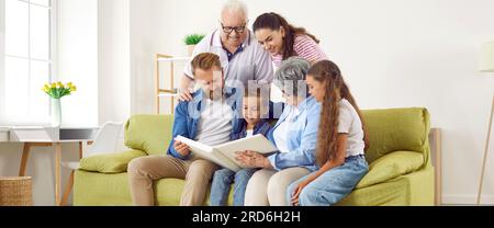 Glückliche Familieneltern, Kinder, Großeltern schauen sich zusammen im Wohnzimmer ein Familienfoto an. Stockfoto