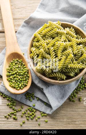 Mungbohnen-Fusilli-Pasta auf altem Holzhintergrund. Schüssel mit roher Pasta und grüner Mungbohne. Glutenfreie Nudeln. Stockfoto