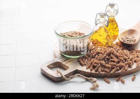 Grüne Fusilli-Nudeln mit Linsen auf grauem Betonhintergrund. Eine Schüssel mit roher Pasta und grünen Linsen. Glutenfreie Pasta. Stockfoto