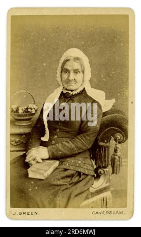 Originales viktorianisches CDV-Porträt aus den 1880er Jahren (Visite-Karte oder Visitenkarte) einer älteren viktorianischen Frau, die sitzt, eine weiße Spitzenkappe trägt und ein Buch hält. Ältere viktorianische Dame. Reife viktorianische Frau. Studio von Joseph Green, Bridge St Caversham, Reading, Berkshire, England, Großbritannien ab 1881. Um 1882 / 1883.. Stockfoto