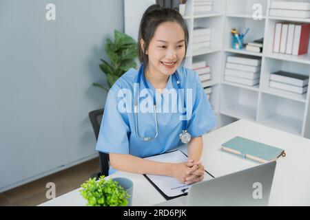 Eine asiatische Ärztin lächelte die Patientin an, die ihr gegenüber saß Stockfoto