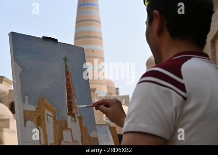 Nahaufnahme eines usbekischen Mannes, der ein Minarett auf einer Leinwand in der Stadt Khiva, Usbekistan, malt Stockfoto