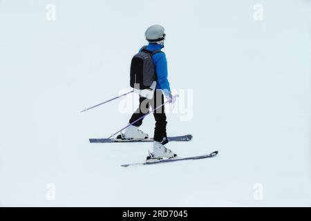 Skisport im Winter. Skifahrer in blauem Skianzug steigt auf dem Lift die Berghänge hinauf. Urlaub in den Bergen im Skigebiet. Stockfoto