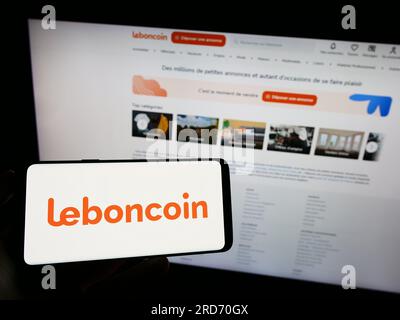 Person, die ein Mobiltelefon mit dem Logo des französischen Anzeigenunternehmens Leboncoin auf dem Bildschirm vor der Unternehmenswebseite hält. Konzentrieren Sie sich auf das Display des Telefons. Stockfoto