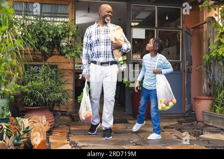 afroamerikanischer Großvater und Enkel mit Einkaufstaschen im Bio-Lebensmittelgeschäft Stockfoto