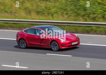 2019 Red Tesla 3 Standard Range + Red Car Limousine Electricity 177 kW; Fahren mit hoher Geschwindigkeit auf der Autobahn M6 im Großraum Manchester, Großbritannien Stockfoto