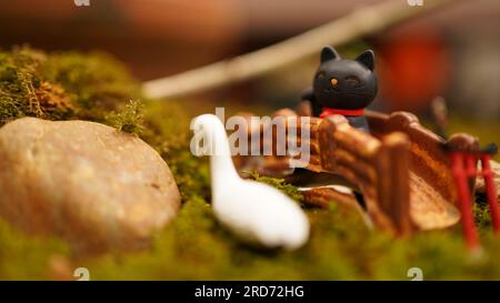 Miniaturkatze und Gans auf einer niedlichen kleinen Landschaft mit Brücke Stockfoto