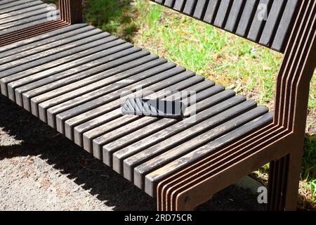 Vergessenes Smartphone auf der Holzbank im Stadtpark. Verlorenes Handy im Park Stockfoto