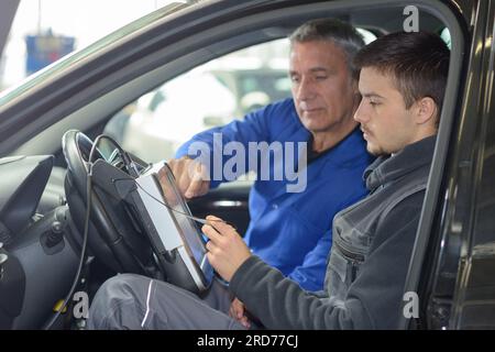 Schüler mit Lehrer, die Reparatur eines Autos während der Lehrzeit Stockfoto