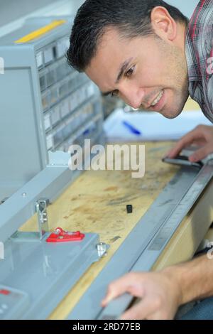 Mann, der in der Werkstatt an der Metallstange gemessen wird Stockfoto