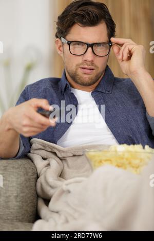 Ein Mann, der Popcorn isst, während er fernsieht Stockfoto