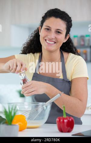 Die Chefköchin zerkleinert gemischten schwarzen Pfeffer in einem Topf Stockfoto