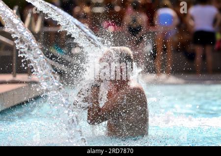 19. Juli 2023, Baden-Württemberg, Sigmaringen: Ein Mann erfrischt sich unter einem Brunnen im Donaubad. Bis zum Wochenende bleibt das Wetter in Baden-Württemberg mit Temperaturen bis 29 Grad sommerfreundlich - aber auch Duschen sind zu erwarten. Foto: Thomas Warnack/dpa Stockfoto