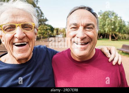 Zwei männliche Seniorenfreunde, die Spaß beim Training haben Laufen im Stadtpark - glückliche, reife Männer, die Fitness im Freien machen - Sport und elendig gesund l Stockfoto