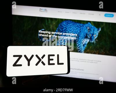 Person, die ein Smartphone mit dem Logo der Zyxel Communications Corporation auf dem Bildschirm vor der Website hält. Konzentrieren Sie sich auf das Display des Telefons. Stockfoto