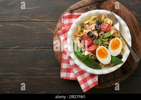 Italienischer Nudelsalat. Orekchiette Pasta mit Thunfisch, Tomatenkirsche, Oliven, Basilikum und Parmesan auf einem dunklen Holztisch mit altem rustikalem Hintergrund. Stockfoto