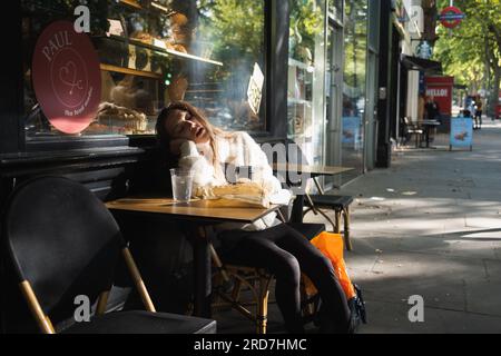 Attraktive Frauen in ihren Zwanzigern schlafen draußen in einem Café in der Holland Park Avenue, London Stockfoto