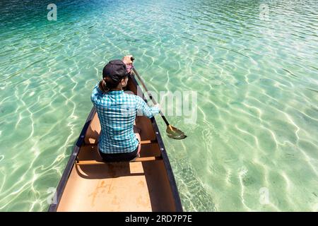 Frau Touristin paddelt in einem Kanu auf einem spektakulären Weissensee in Kärnten in Österreich, karibisches Wasser an einem schönen sonnigen Sommertag Stockfoto