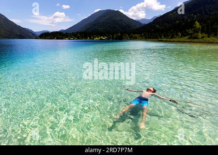 Kindertourist genießt Schulferien an einem spektakulären Weissensee in Kärnten in Österreich, karibisches Wasser an einem schönen sonnigen Sommertag Stockfoto