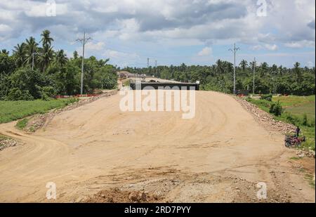 Tiaong, Philippinen. 19. Juli 2023: Laufende Arbeiten an einem der größten philippinischen Projekte. Brücken und Straßen durchqueren Reisfelder und Wälder. Die South Luzon Expressway toll Road 4 (SLEX TR4) ist Teil des längsten Autobahnprojekts des Landes, das Manila zunächst mit Lucena und dann mit dem 2022 unterzeichneten Projekt SLEX TR5 nach Matnog verbinden wird. Die die Provinzen Quezon und Bicol über eine 420 km lange Mautstraße miteinander verbinden. Am Dienstag unterzeichnete Pres. Marcos ein Gesetz über Staatsfonds im Wert von $9 Milliarden US-Dollar, mit dem Wirtschaftswachstum, Straßen und Infrastruktur gefördert werden sollen. Kredit: Kevin Izorce/Alamy Live News Stockfoto