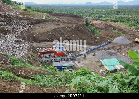 Malepunyo Mountains Range, Philippinen. 19. Juli 2023 : Mobile Stone Jaw zerbricht Steinbrüche in den Bergen, um Sand, Kies und zerkleinerte Steine für den SLEX TR4 bereitzustellen. Die South Luzon Expressway toll Road 4 ist Teil des längsten Autobahnprojekts des Landes, das Manila zunächst mit Lucena und dann mit dem 2022 unterzeichneten SLEX TR5-Projekt nach Matnog verbinden wird, das die Provinzen Quezon und Bicol über eine 420 km lange Straße verbinden wird. Seit seiner Wahl haben mehrere Umweltschutzgruppen Press Marcos aufgefordert, die Entwaldung, den Abbau und die Gewinnung von Steinen und Erden zu verringern. Kredit: Kevin Izorce/Alamy Live News Stockfoto