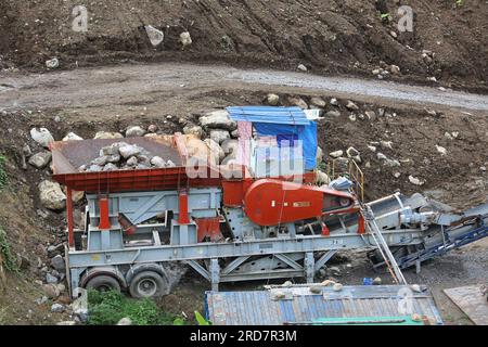 Malepunyo Mountains Range, Philippinen. 19. Juli 2023 : Mobile Stone Jaw zerbricht Steinbrüche in den Bergen, um Sand, Kies und zerkleinerte Steine für den SLEX TR4 bereitzustellen. Die South Luzon Expressway toll Road 4 ist Teil des längsten Autobahnprojekts des Landes, das Manila zunächst mit Lucena und dann mit dem 2022 unterzeichneten SLEX TR5-Projekt nach Matnog verbinden wird, das die Provinzen Quezon und Bicol über eine 420 km lange Straße verbinden wird. Seit seiner Wahl haben mehrere Umweltschutzgruppen Press Marcos aufgefordert, die Entwaldung, den Abbau und die Gewinnung von Steinen und Erden zu verringern. Kredit: Kevin Izorce/Alamy Live News Stockfoto