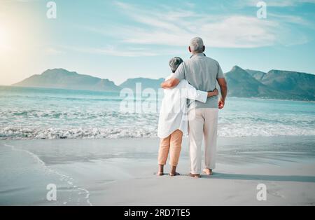 Zurück, Umarmung oder altes Paar am Strand, um sich mit Liebe, Pflege oder Unterstützung im Sommerurlaub in der Natur zu entspannen. Ruhestand, reifer Mann oder Seniorin auf See oder Stockfoto