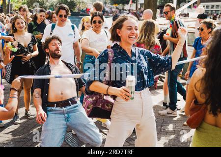 Amsterdam, Nordholland, Niederlande – 6. August 2022: Eine Menge Leute, die Pride Amsterdam feiern, nehmen freudig am Limbo-Tanz Teil Stockfoto