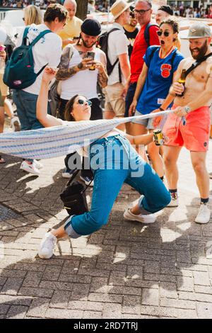 Amsterdam, Nordholland, Niederlande – 6. August 2022: Eine Frau tanzt auf einer Straße zu einer Menschenmenge, die während des „Pride Amsterdam“ jubelt Stockfoto