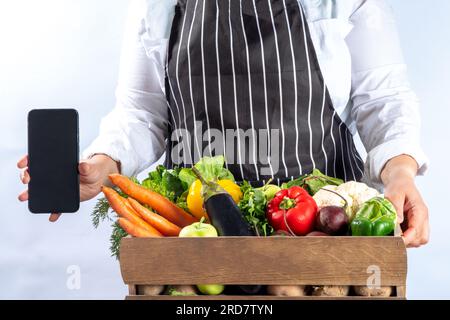 Bauernhof-Bio-Markt-Shopping-Konzept, Holzkiste mit Sommer, rohem Gemüse und Obst im Herbst, in den Händen von Bauernfrauen auf weißem Hintergrund Stockfoto