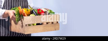 Bauernhof-Bio-Markt-Shopping-Konzept, Holzkiste mit Sommer, rohem Gemüse und Obst im Herbst, in den Händen von Bauernfrauen auf weißem Hintergrund Stockfoto