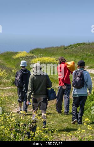 Eine Gruppe männlicher Freunde, die entlang der Warren am Pentire Point East in Newquay in Cornwall in Großbritannien, Europa spazieren Stockfoto