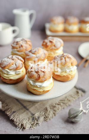 Cremepuffs gefüllt mit Vanillecreme und Schlagsahne auf einem weißen Teller Stockfoto