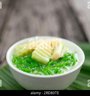 Nahaufnahme von Lod Chong Thai Dessert aus Reismehl auf Kokosnusssirup und Pandanblättern auf Holzhintergrund. Stockfoto