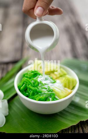 LOD Chong wird mit frischer Kokosmilch auf Bananenblatt auf Holzhintergrund gegossen Stockfoto