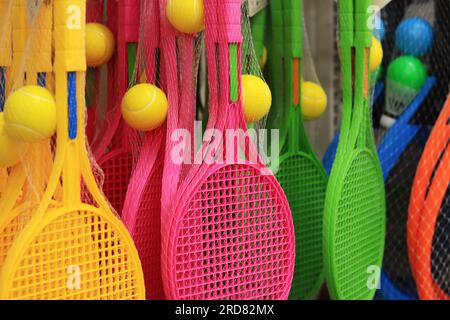 Tennisschläger in verschiedenen Farben im Geschäft. Tennisschläger und Ball aus Plastik in einem Set zum Verkauf. Helle Tennissets Stockfoto