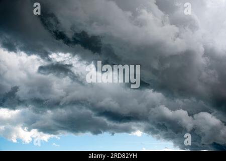 Bedrohliche Wolkenschichten bilden eine gerade Linie mit einem Streifen klaren Himmels, der einen dunkleren Regenstreifen zeigt. Stockfoto