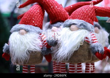 Spielzeugzwerge in roten Hüten, die sich über die Augen zogen und Bärte trugen. Ein Spielzeugset für die Innendekoration an Neujahr oder Weihnachten. Lustige Zwerge Stockfoto