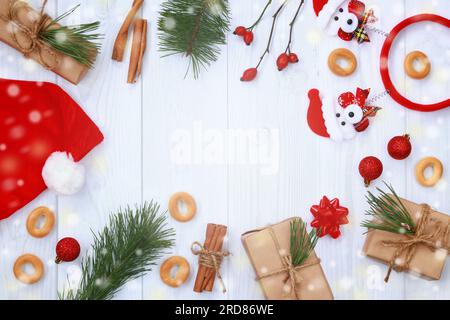 Neujahrshintergrund, Rahmen aus Objekten auf hellem Holzhintergrund, Draufsicht. Weihnachtskomposition, festliche Accessoires und Lichtreflexionen Stockfoto