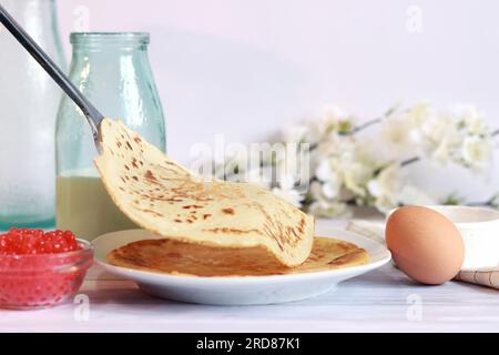 Ein Stapel heiße Pfannkuchen. Legen Sie neue Crepes auf einen Stapel fertig gebackener Pfannkuchen. Großer, runder, dünner Pfannkuchen. Pfannkuchenwoche. Maslenitsa Stockfoto