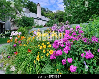 Wohnstraße und Haus mit bunten Blumen im Vorgarten Stockfoto