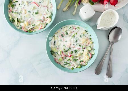 Kalte Sommersuppe Okroshka, Suppe mit Gemüse und Wurst, Eier und frische Kräuter und Joghurt, traditionelle russische Suppe Stockfoto