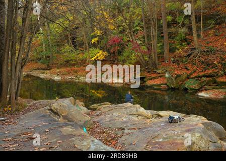 Im Spätherbst versucht ein einsamer, unbekannter Fischer sein Glück am Rocky River; Ort: David Fortier Park in Olmsted Falls, einem Vorort von Cleveland, Ohio Stockfoto