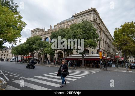 Paris, Île-de-France, Frankreich - 1. Oktober 2022: Frau überquert die Straße und andere Passanten gehen in der Altstadt von Paris durch die Metro Sta Stockfoto