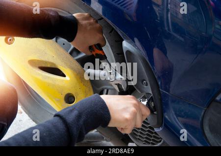 Eine Frau repariert ein Motorrad mit einem Schraubenschlüssel Stockfoto